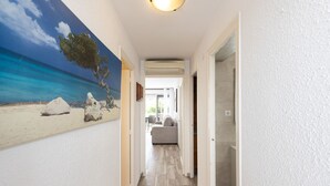 A hallway with a beach mural, a ceiling light, and a view into a living area with a sofa. - C204-058 UHC ANTINEA I APARTAMENTS (Cambrils)