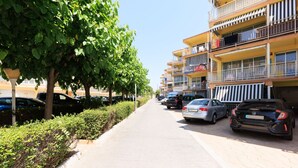 A row of parked cars along a paved sidewalk adjacent to a multi-story building with balconies. - C204-058 UHC ANTINEA I APARTAMENTS (Cambrils)