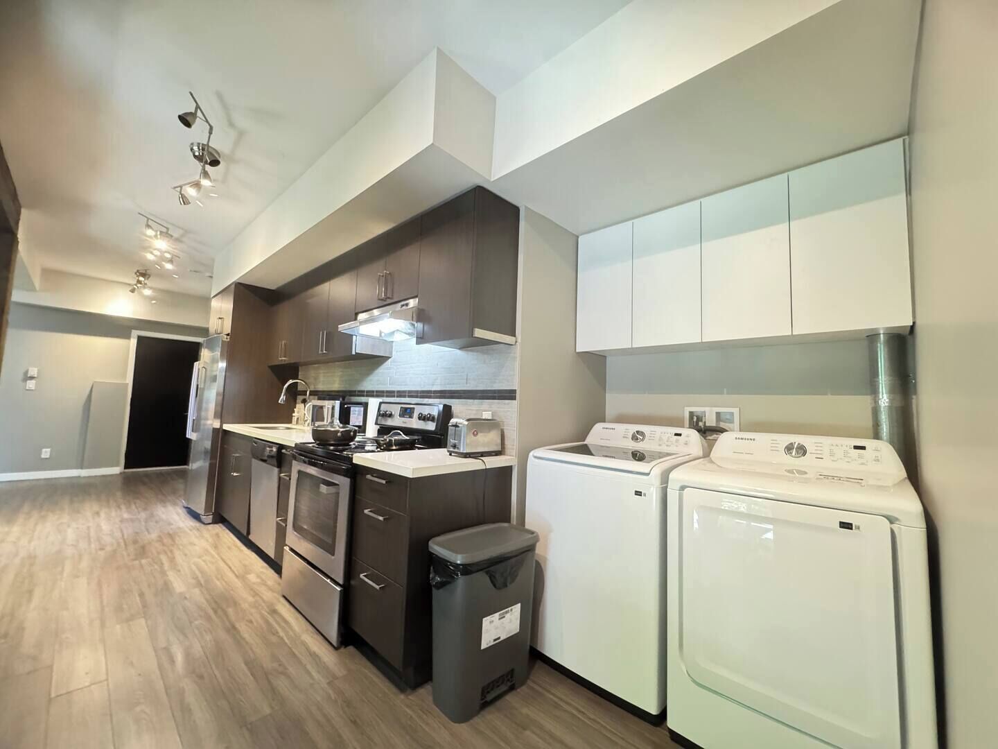 A modern kitchen with a stove, microwave, toaster, and washing machine.