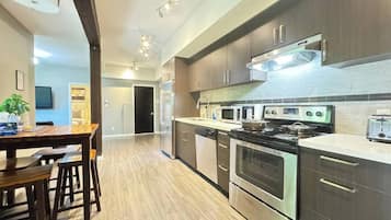 Una cocina moderna con electrodomésticos de acero inoxidable, armarios de madera y un comedor con mesa y sillas de madera.
