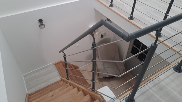 En interiör med flera nivåer, ett trätrapphus och metallräcken.