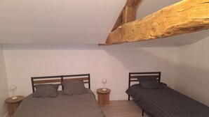 Ett sovrum med två sängar, trägavlar, sängbord med lampor och en synlig träbalk i taket.