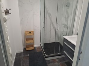A bathroom with a glass-enclosed shower, a wooden shelf, and a black mat. - Accommodation for 6 people (Mareuil-sur-Lay-Dissais)