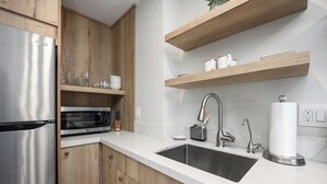 A modern kitchen with a stainless steel refrigerator, microwave, and double sink. Wooden cabinets and a marble countertop are also visible. - Condo on property at LaCosta Golf Resort & Spa with Pool 680 (Carlsbad)