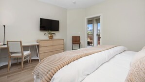 A bedroom with a bed, a desk, a chair, a television, and a view of the outdoors. - Condo on property at LaCosta Golf Resort & Spa with Pool 680 (Carlsbad)
