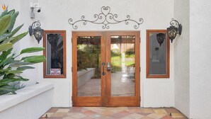 A double wooden door with glass panels, flanked by two wall-mounted light fixtures, leading to a tiled patio area. - Condo on property at LaCosta Golf Resort & Spa with Pool 680 (Carlsbad)