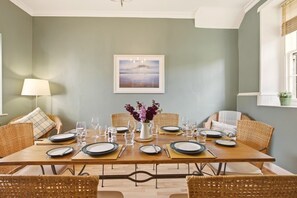 Spacious dining room with wicker chairs and table set for memorable family meals - Millhouse Cottage - North East Escapes (Waren Mill)