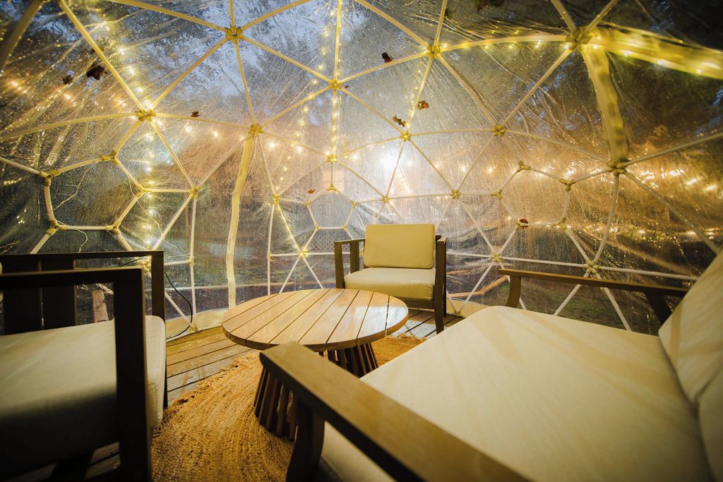 Une structure en forme de dôme géodésique, avec un espace aménagé pour s’asseoir à l’intérieur.