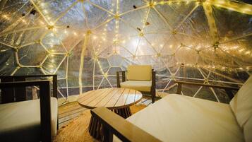 A geodesic dome structure with a seating area inside.