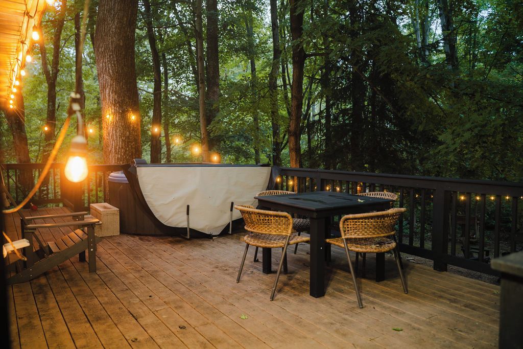 Una terrazza esterna con tavolo e sedie, immersa tra alberi e luci decorative.
