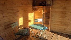 L’intérieur d’un chalet en bois comprend une table et des chaises, une petite étagère avec un jeu d’échecs et une fenêtre qui laisse entrer la lumière du soleil.