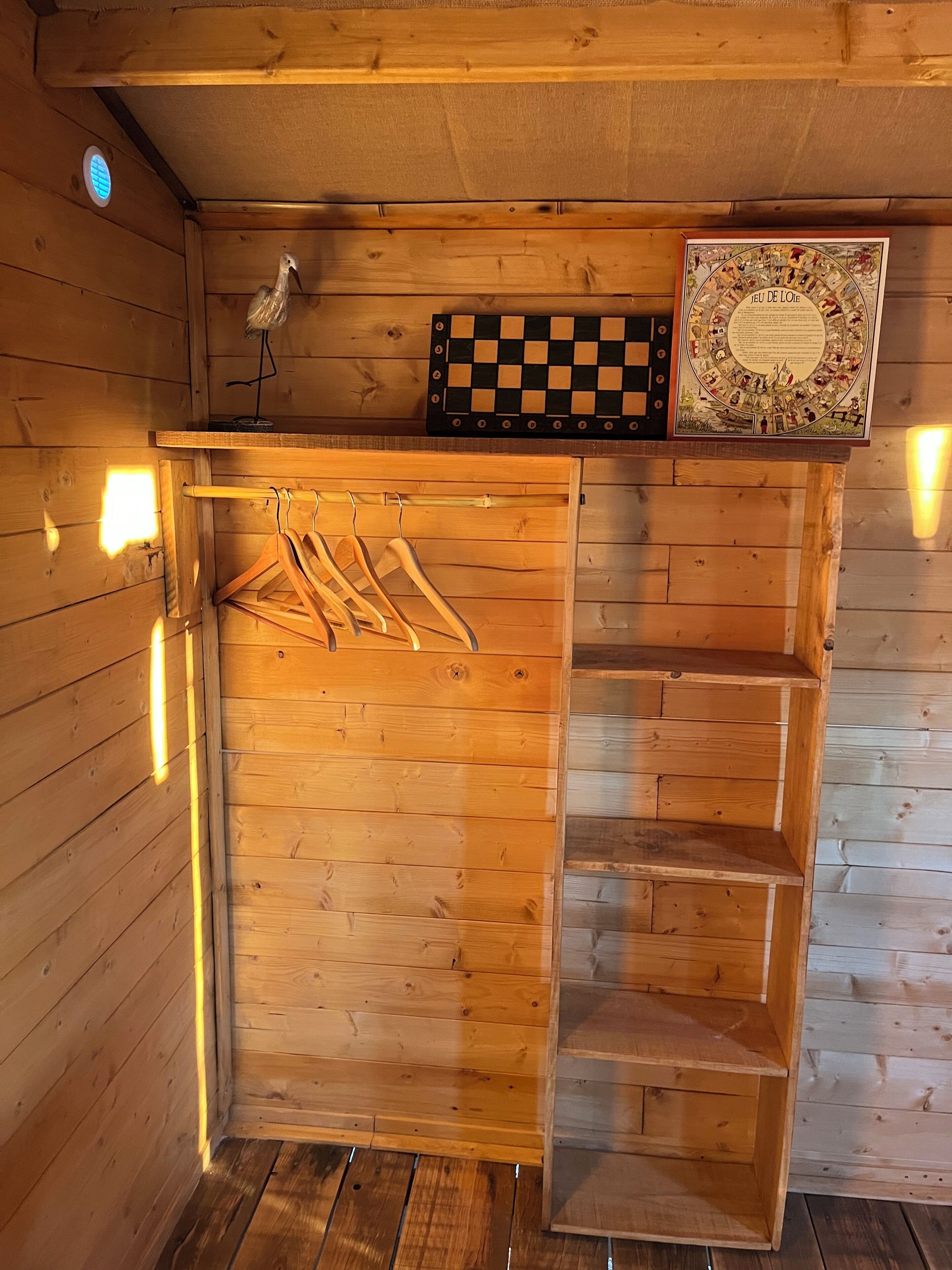 A wooden interior with a chessboard, a framed picture, and a drying rack.