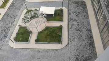 En vy från ovan av ett parkliknande område med en central byggnad, omgivet av grönska och belagda gångvägar.