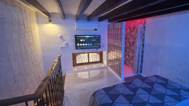 A staircase with a TV mounted on the wall, a patterned floor, and a decorative wall panel. - DUPLEX IN PALMA'S OLD TOWN (Palma)