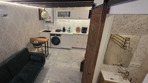 A compact living space with a sofa, a washing machine, and a small kitchen area. - DUPLEX IN PALMA'S OLD TOWN (Palma)