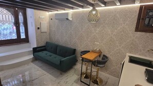A room with a sofa, a small table, a decorative hanging light, and a bathroom with a sink and mirror. - DUPLEX IN PALMA'S OLD TOWN (Palma)