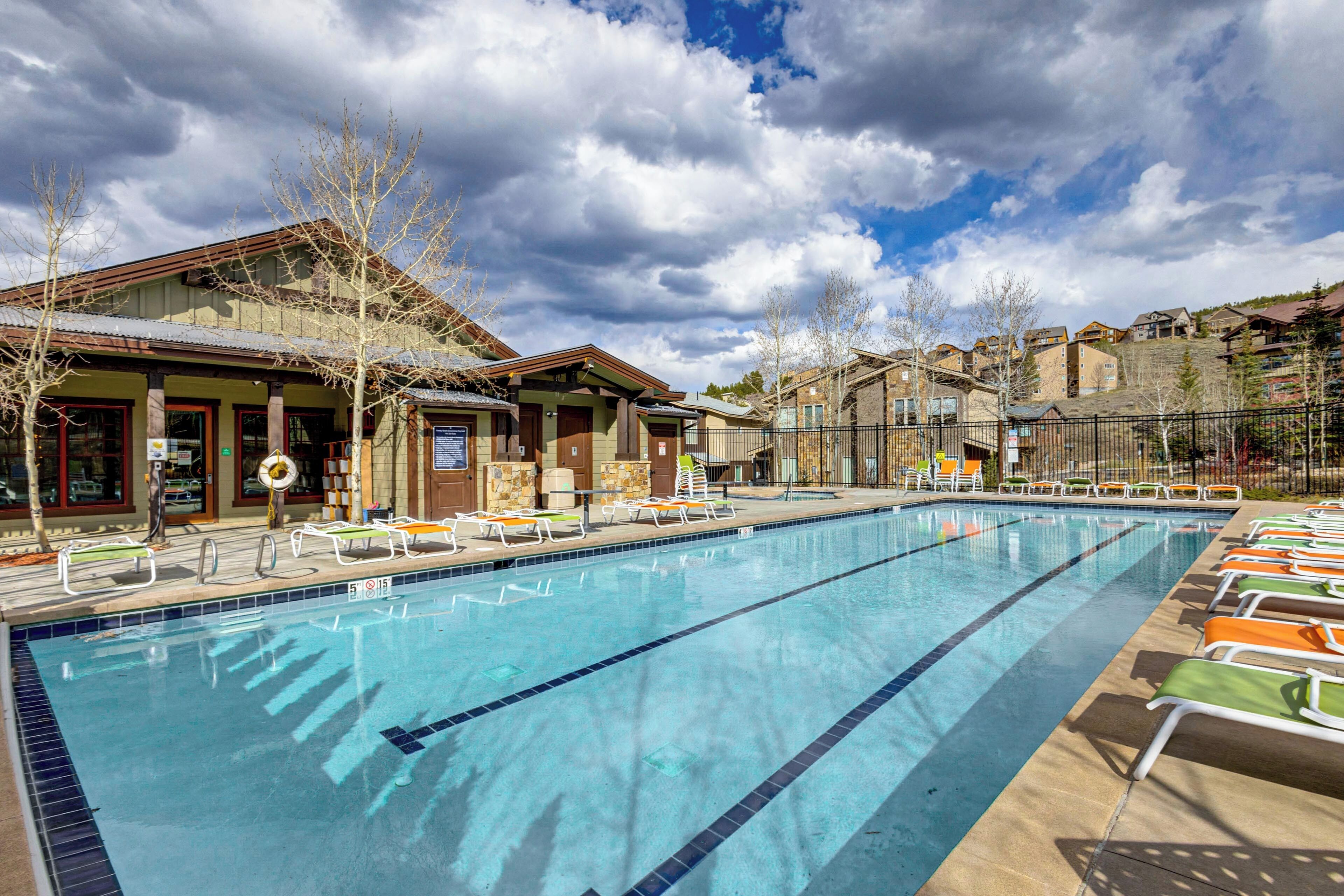 A swimming pool with lounge chairs, a building with a sloped roof, and a cloudy sky.