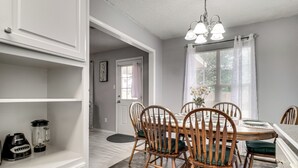 A dining area with a wooden table and chairs, a chandelier, and a window with blinds. - 2 Mi to Texas Tech: Pet-friendly Home, Fenced Yard (Lubbock)