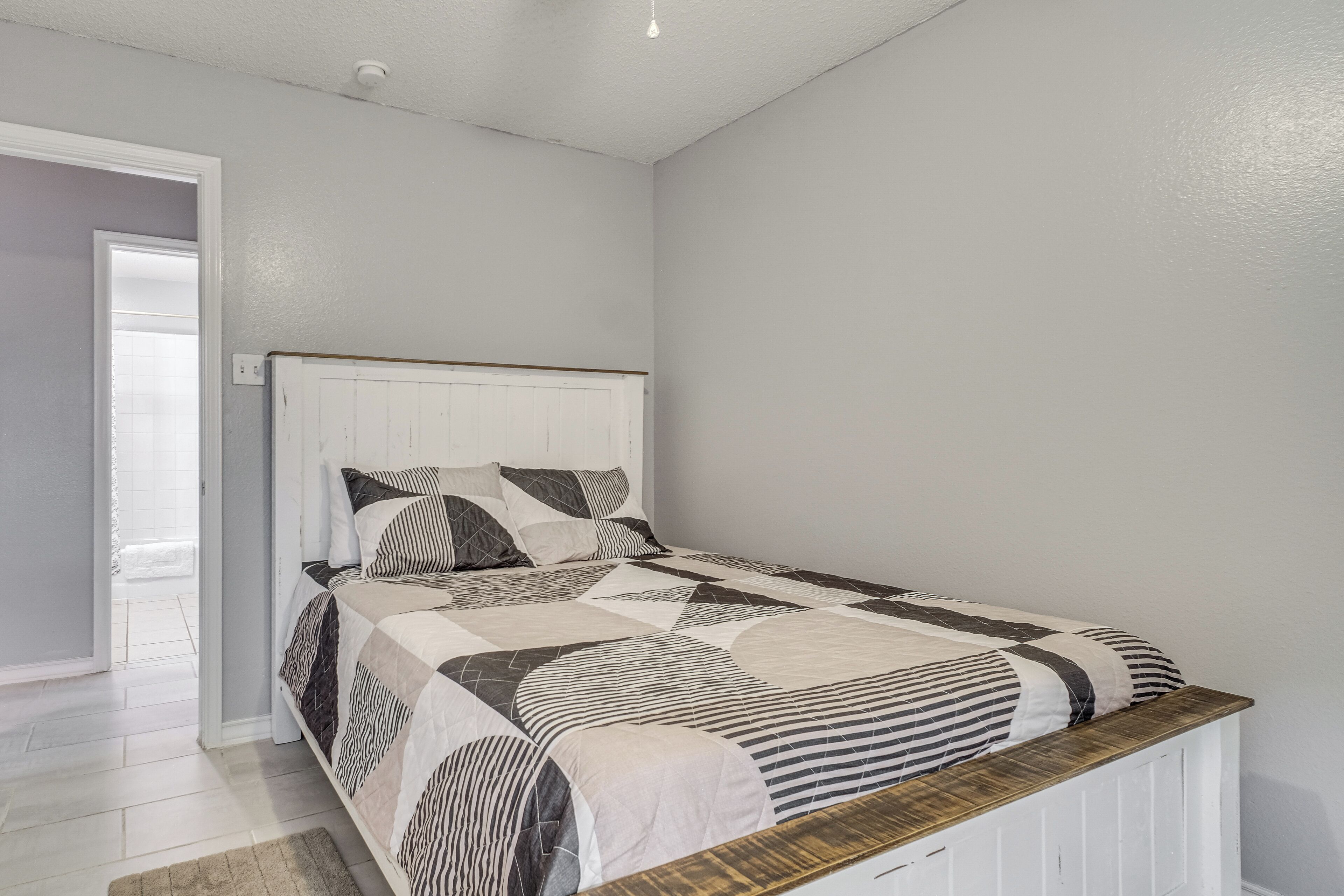 Une chambre à coucher avec un lit, une tête de lit en bois et une porte blanche.