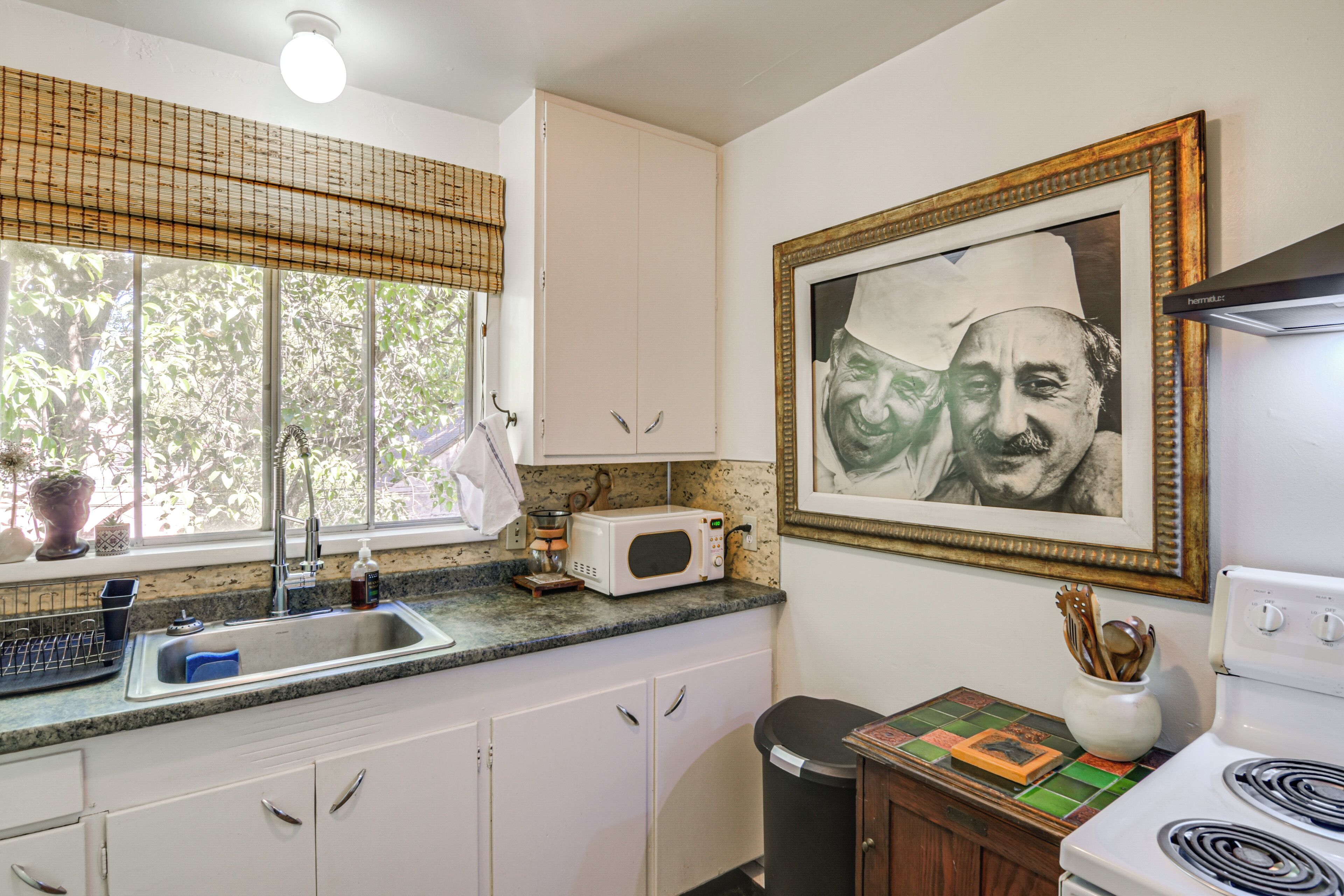 A kitchen with white cabinets, a microwave, a sink, and a stove.