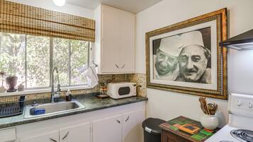 A kitchen with white cabinets, a microwave, a sink, and a stove.