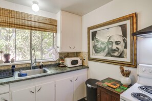 A kitchen with white cabinets, a microwave, a sink, and a stove.
