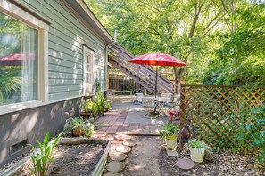 A patio with a wooden deck, outdoor furniture, and a red umbrella.