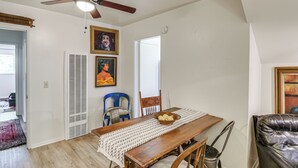 A dining area with a wooden table, chairs, a ceiling fan, and artwork on the walls.