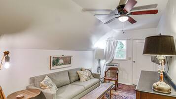 A living room with a ceiling fan, a sofa, a bench, a lamp, and a window with curtains.