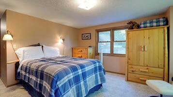 A bedroom with a bed, bedside lamps, a dresser, a window, and a bench.