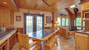 A wooden interior with a large dining table, benches, and a kitchen area with a wood stove. - Boat, Fish & Unwind: Family Cabin on Bad Axe Lake (Park Rapids)