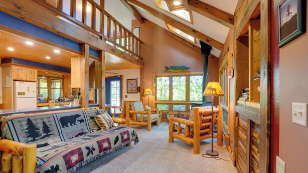 A spacious living room with a high ceiling, wooden beams, a large sofa, and a fireplace. - Boat, Fish & Unwind: Family Cabin on Bad Axe Lake (Park Rapids)