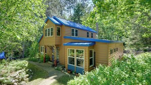 A wooden cabin with a blue roof, surrounded by trees and a garden. - Boat, Fish & Unwind: Family Cabin on Bad Axe Lake (Park Rapids)