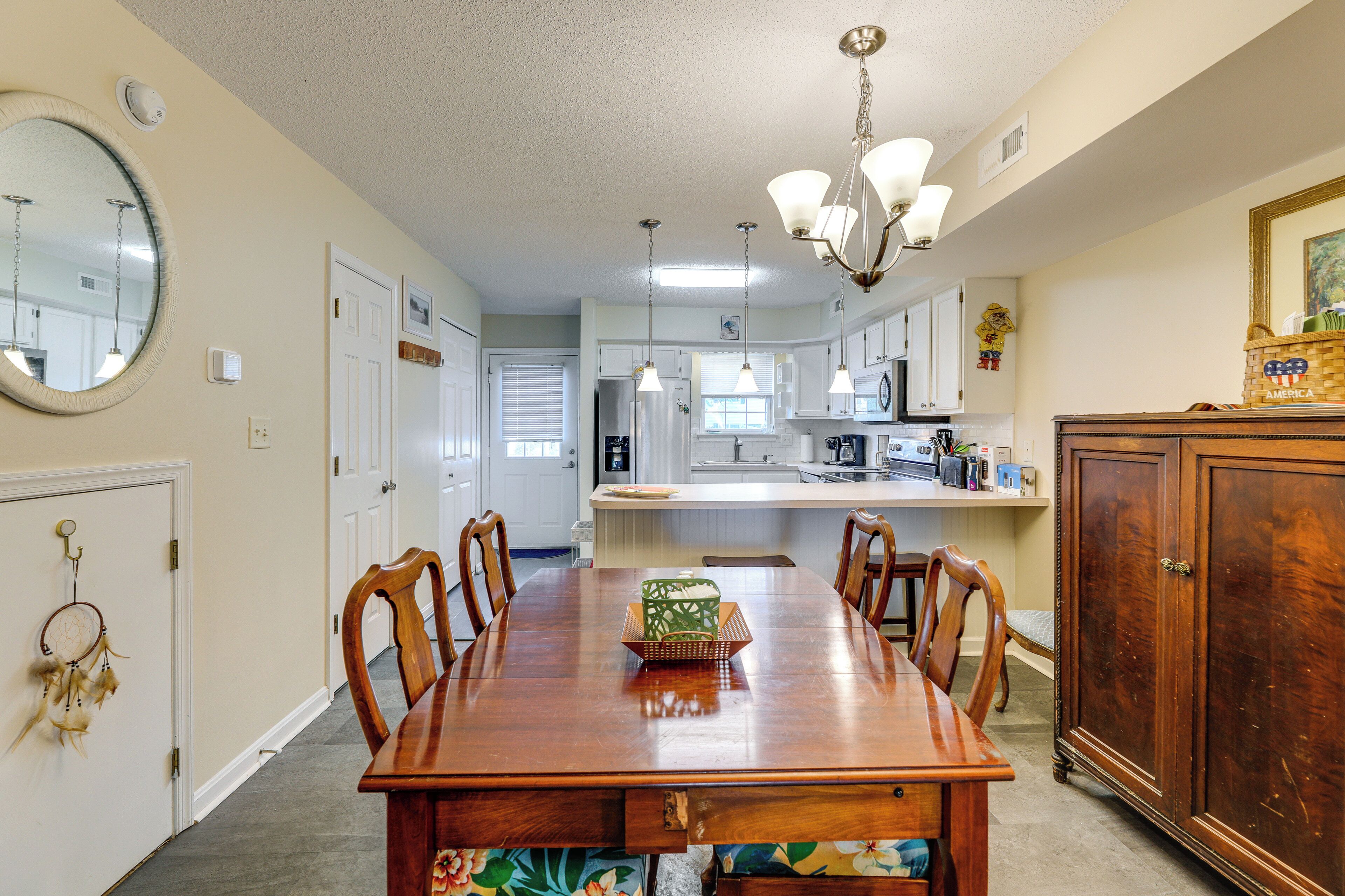 A dining room with a wooden table, chairs, and a chandelier.
