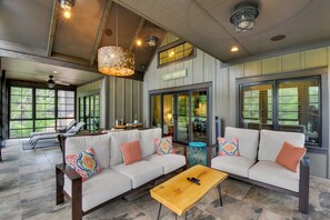 A spacious living area with a large sectional sofa, a wooden coffee table, and a dining area with a table and chairs. - Waterfront Lake Keowee Home w/ Hot Tub & Views! (West Union)