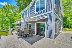 A two-story building with a deck, outdoor seating, and a view of the surrounding greenery. - Boathouse, Dock & Sunset Views! Muskrat Lake Home (Gobles)