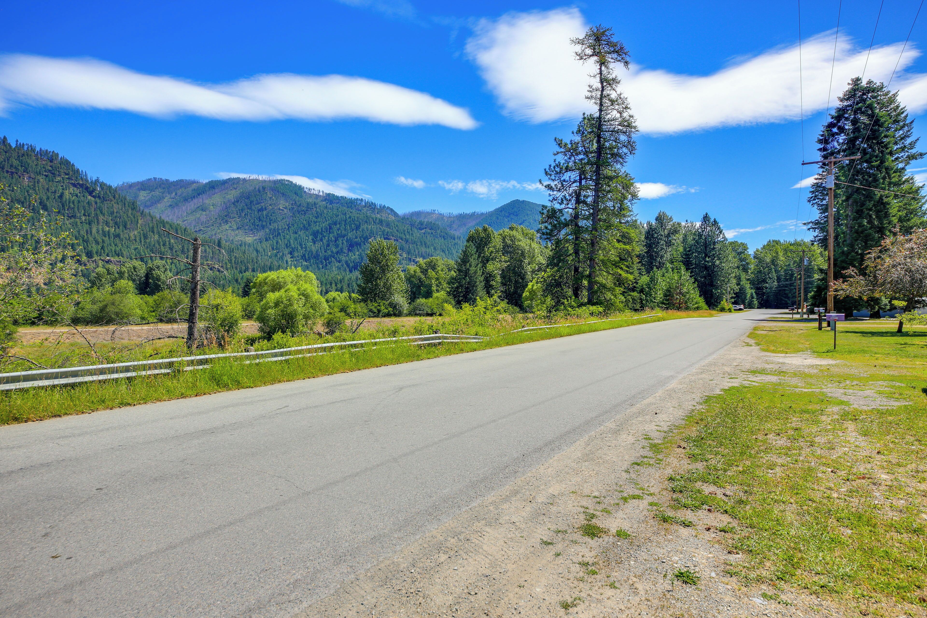 A road curving through a mountainous area with dense forests on both sides.