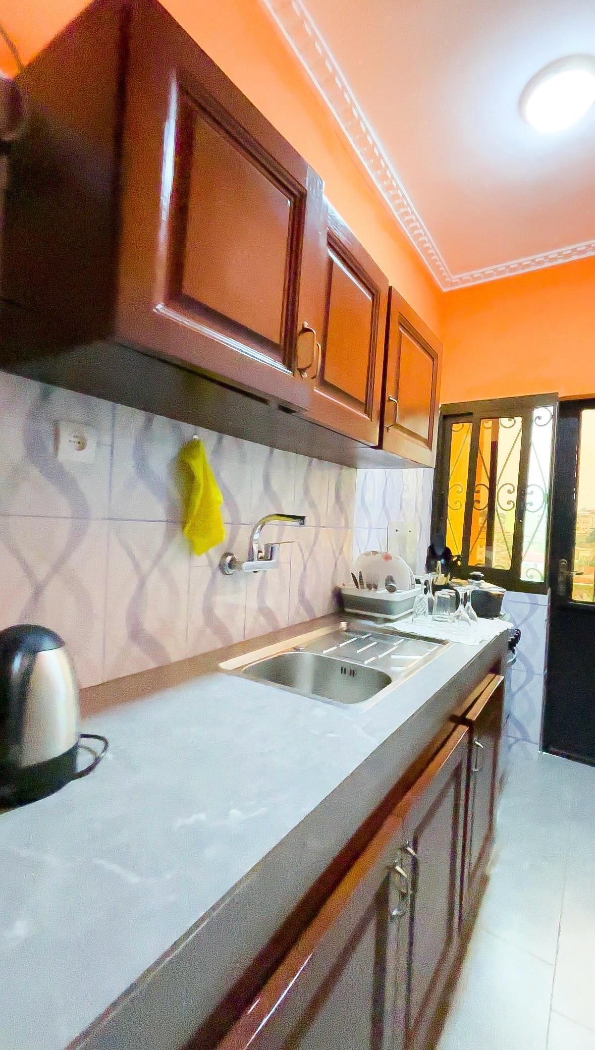 A kitchen with wooden cabinets, a sink, and a window with decorative iron bars.