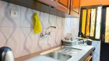 A kitchen with wooden cabinets, a sink, and a window with decorative iron bars.
