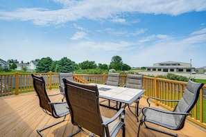 A deck with a table and chairs, surrounded by a wooden railing.