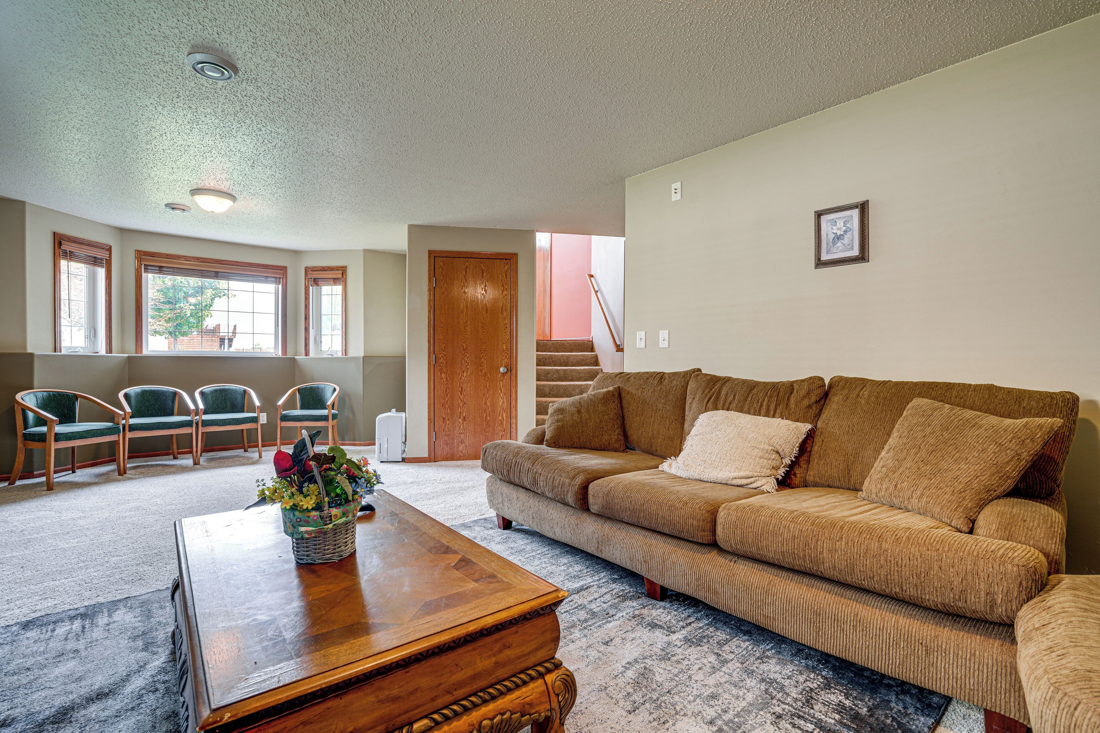 A living room with a brown sofa, wooden coffee table, and green chairs.