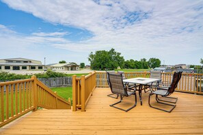 A wooden deck with a table and chairs, surrounded by a wooden fence, overlooking a residential area.
