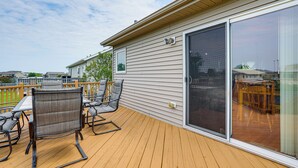 A deck with outdoor furniture, a sliding glass door, and a view of other houses.
