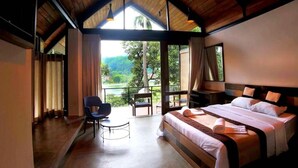 Un dormitorio con una cama grande, una silla, un escritorio y vistas al exterior.