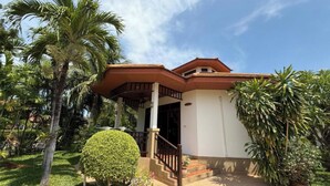 A house with a porch, a staircase, and a garden with palm trees. - Premium Long-Stay Villa - Pool, Garden, Near the Beach, 2 Bedrooms, 90 square meters (Hua Hin District)