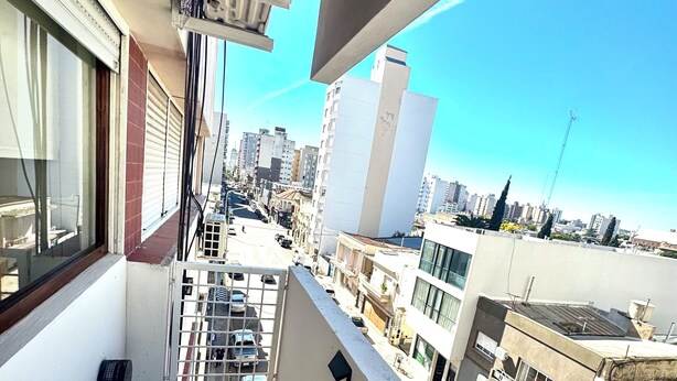 A balcony with a view of a cityscape, including buildings and a clear sky.