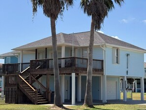 A two-story house with a balcony, a staircase, and a garage. - Super Cute 2 bedroom, close to beach, affordable! (Crystal Beach)