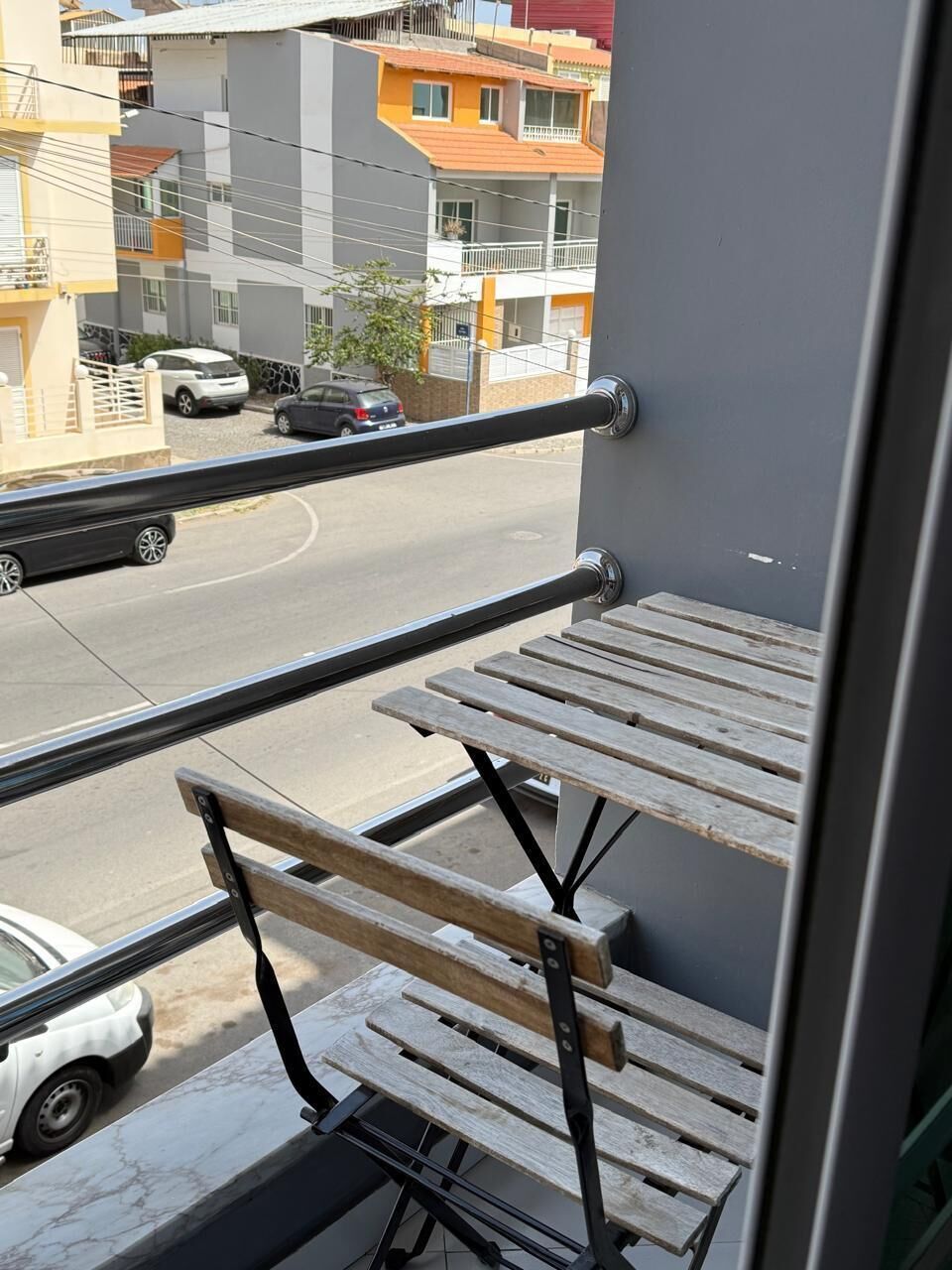 A balcony with two wooden benches and a metal railing.