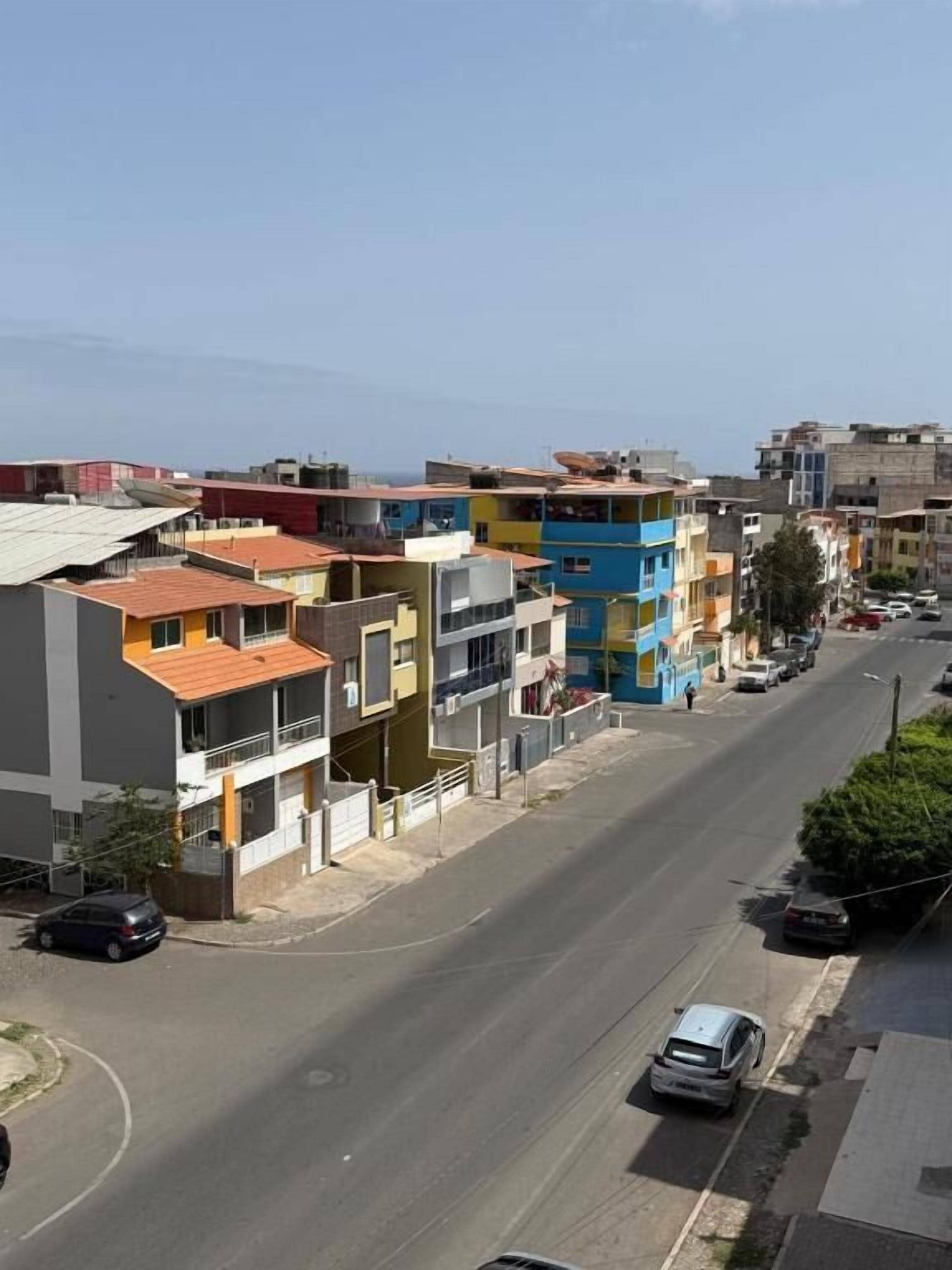 Un immeuble à plusieurs étages doté de balcons, une rue devant et des voitures garées.