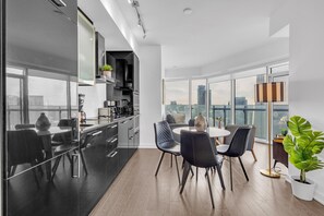 Uma cozinha moderna com armários pretos e uma área de jantar com uma mesa redonda e cadeiras pretas.